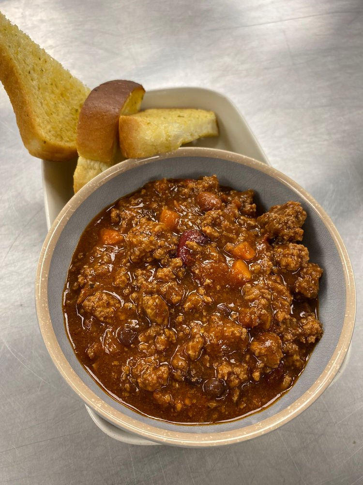 A bowl of chili with a bread stick